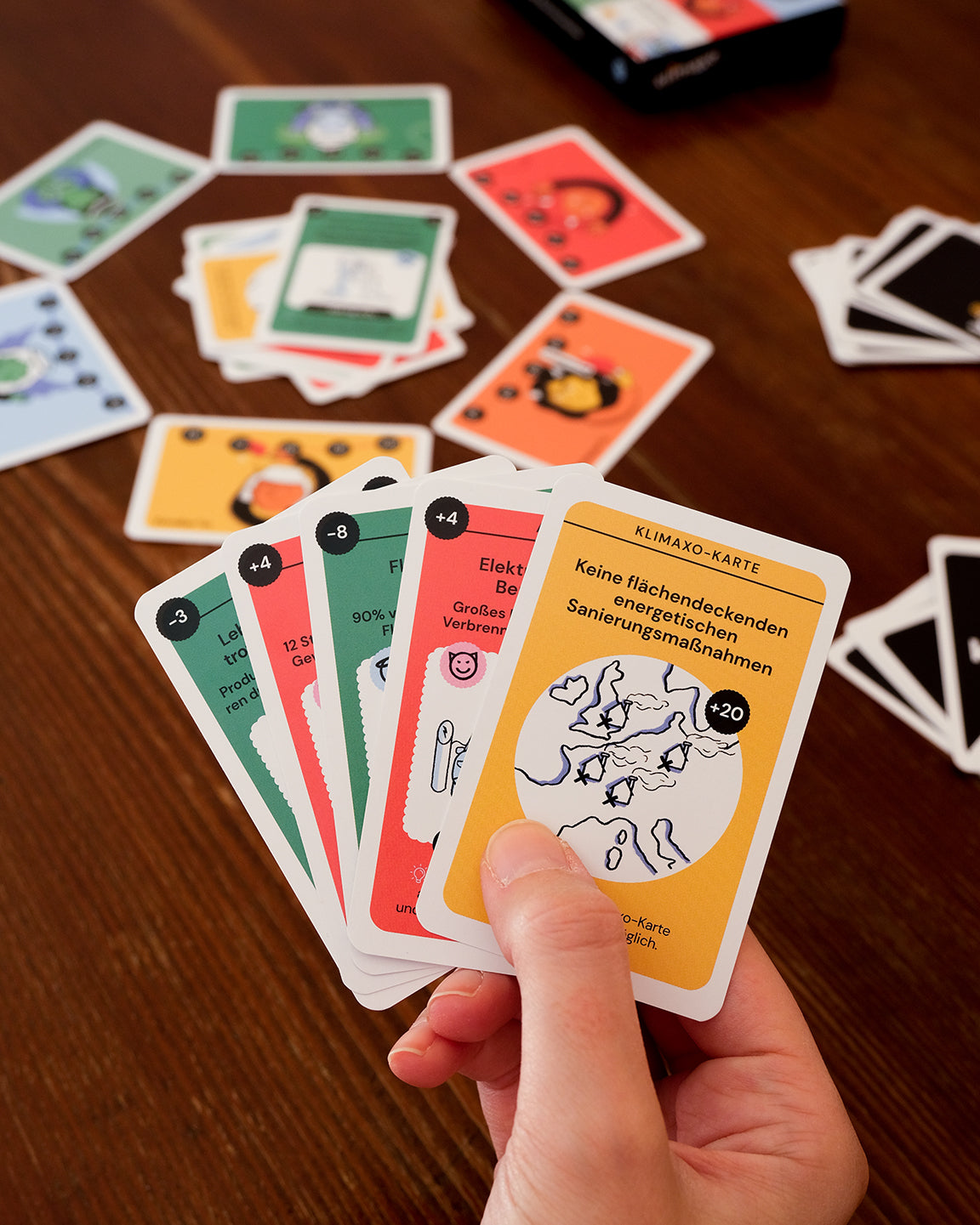 Spielkarten des nachhaltigen Klimaspiels Klimaxo auf der Hand